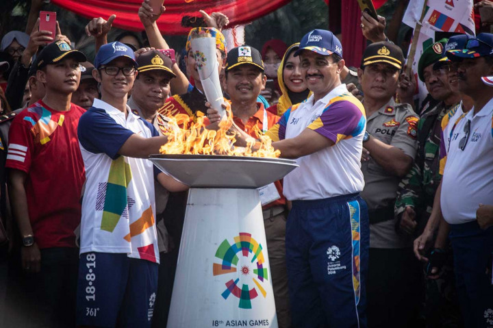 Wali Kota Jakarta Timur M Anwar (kanan) menyerahkan obor Asian Games 2018 kepada atlet Taekwondo Priyaka Ivan Astama saat prosesi Torch Relay Asian Games 2018 di kawasan Kramat Jati, Jakarta Timur, Rabu, 15 Agustus 2018.