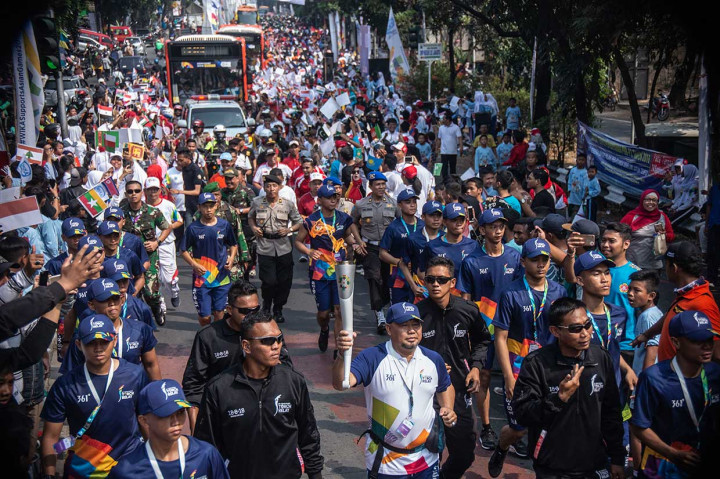Tokoh agama Muhammad Thamrin (tengah) membawa obor saat prosesi Torch Relay Asian Games 2018 melintas di Jalan Raya Pondok Gede, Jakarta Timur.