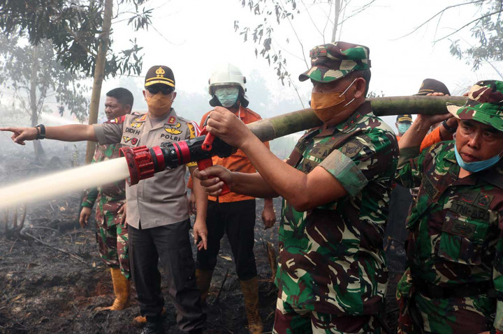 Pangdam XII Tanjungpura Mayjen Achmad Supriyadi (kedua kanan) bersama Kapolda Kalbar Irjen Didi Haryono (kiri) menyemprotkan air untuk memadamkan kebakaran lahan gambut di Jalan Sepakat, Pontianak, Kamis, 16 Agustus 2018. 