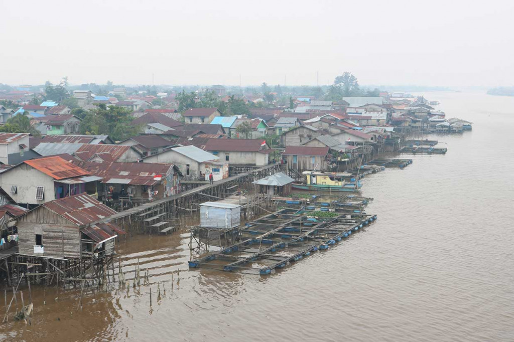 Kebakaran lahan membuat permukiman warga Pontianak di tepian Sungai Kapuas diselimuti kabut asap.
