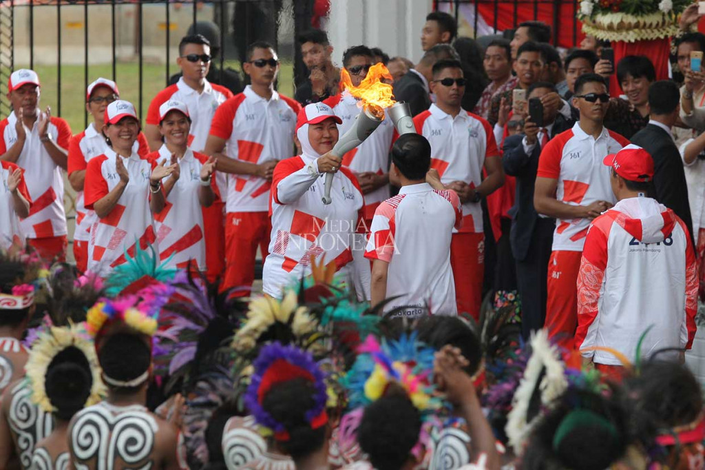 Presiden Joko Widodo didampingi Menteri Pemuda dan Olahraga Imam Nahrawi berlari kecil menyambut obor Asian Games yang telah masuk di pintu gerbang Istana Merdeka, Jakarta. Presiden menerima api obor tersebut dari atlet bulu tangkis legendaris Verawaty Fajrin.