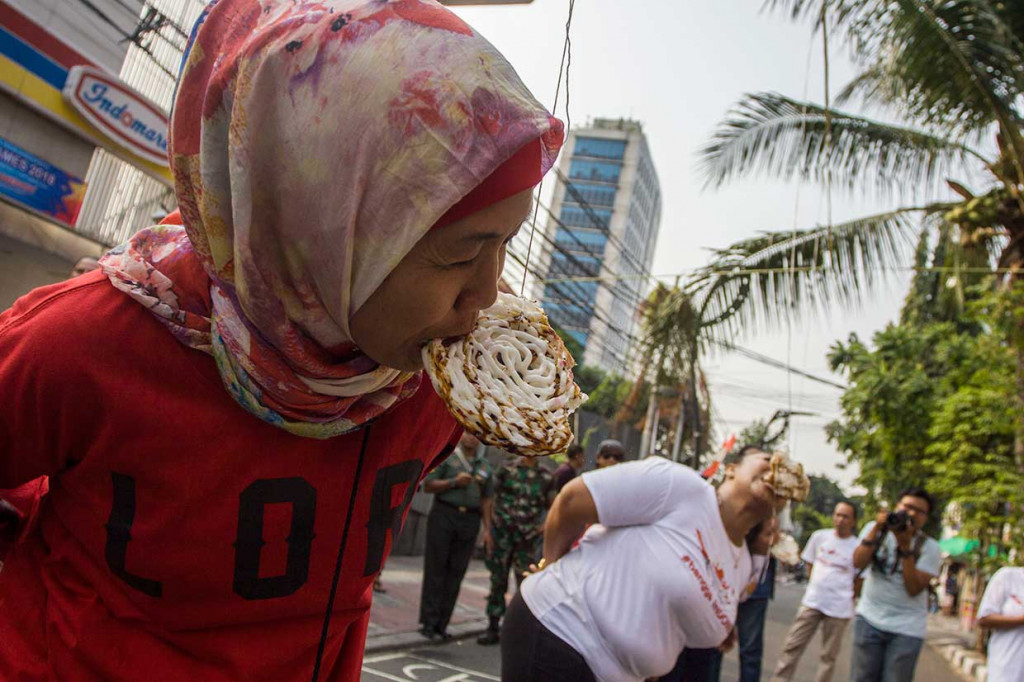 Warga mengikuti lomba makan kerupuk di Jalan Jaksa, Jakarta. Antara Foto/Galih Pradipta