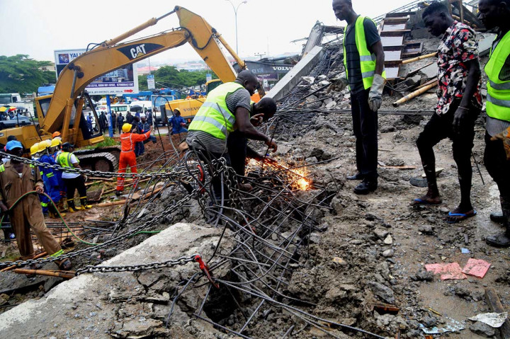 Tim SAR tengah berusaha keras menyingkirkan beton dengan menggunakan las untuk mengevakuasi orang yang diduga terperangkap reruntuhan bangunan di Abuja, Nigeria, Jumat, 17 Agustus waktu setempat. Petugas juga dibantu alat berat.