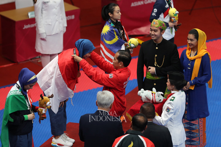 Presiden Joko Widodo mengalungkan medali emas kepada Atlet Taekwondo Indonesia Defia Rosmaniar di Plenary Hall Jakarta Convention Centre. MI/Ramdani