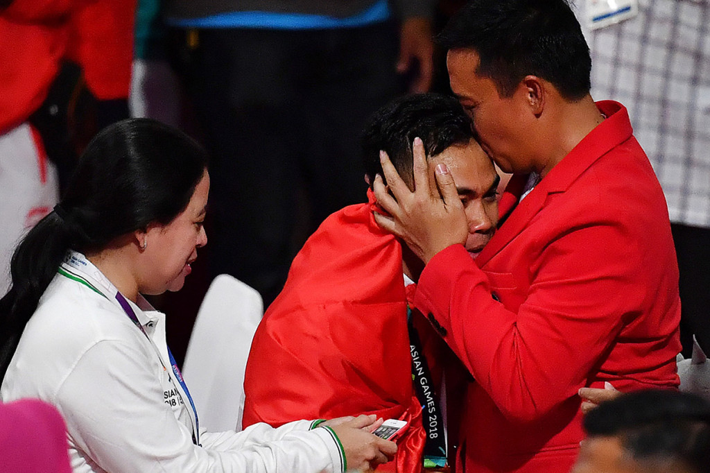 Menpora Imam Nahrawi (kanan) mengecup kening lifter Indonesia Eko saat penyerahan medali pada nomor angkat besi putra 62 kg Group A Asian Games ke-18 2018 di JiExpo Jakarta. Antara Foto/INASGOC/Fanny Octavianus
