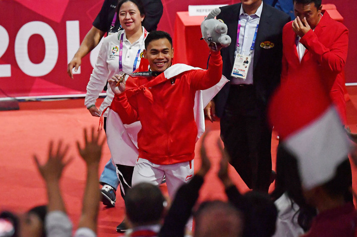 Menko PMK Puan Maharani (kiri) dan Menpora Imam Nahrawi (kanan) mendampingi lifter Indonesia Eko Yuli Irawan menyapa penonton usai nomor angkat besi putra 62 kg Group A Asian Games ke-18 2018 di JiExpo Jakarta. Antara Foto/INASGOC/Fanny Octavianus