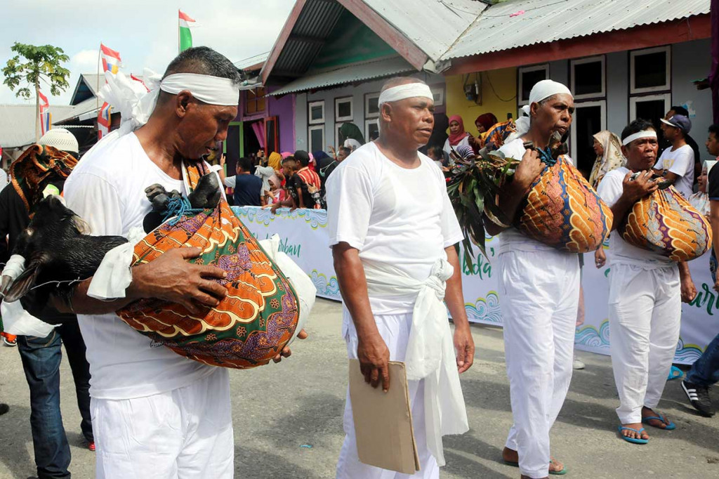 Tiga warga menggendong tiga kambing sebagai kaul kurban pada ritual tradisi Abda'u di Desa Tulehu, Pulau Ambon, Maluku, Rabu, 22 Agustus 2018.