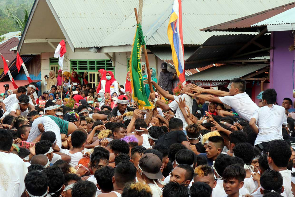 Puluhan pemuda melompat ke tengah pemuda lainnya saat berebutan selembar bendera hijau bertuliskan Lailaha Ilallah Muhammadarrasulullah (Kami bersaksi tiada Tuhan selain Allah dan Muhammad adalah utusan Allah) pada perayaan tradisi Abda'u.