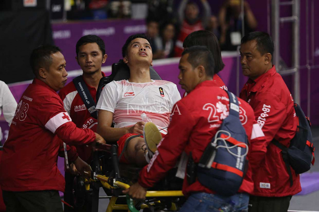 Anthony Sinisuka Ginting harus dibawa keluar lapangan dengan alat bantu oleh petugas medis setelah mengalami cedera saat melawan pebulutangkis Tiongkok Shi Yuqi pada laga pertama babak final beregu putra Asian Games 2018 di Istora Senayan, Jakarta, Rabu, 23 Agustus 2018 malam. 