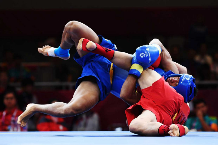 Puja Riyaya (atas) saat beradu jurus dengan atlet wushu Tiongkok Zhanwei Shi di semifnal sanda putra 70 kg. INASGOC/Antara Foto/Akbar Nugroho Gumay