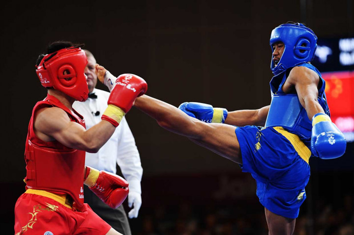 Atlet wushu Indonesia Yusuf Widiyanto (kiri) saat bertarung melawan atlet wushu Tiongkok Guoshun Shen dalam partai semifinal Sanda Putra 56 kg. Secara keseluruhan, wushu telah menyumbang satu emas, satu perak, dan tiga perunggu bagi Indonesia. INASGOC/Antara Foto/Akbar Nugroho Gumay