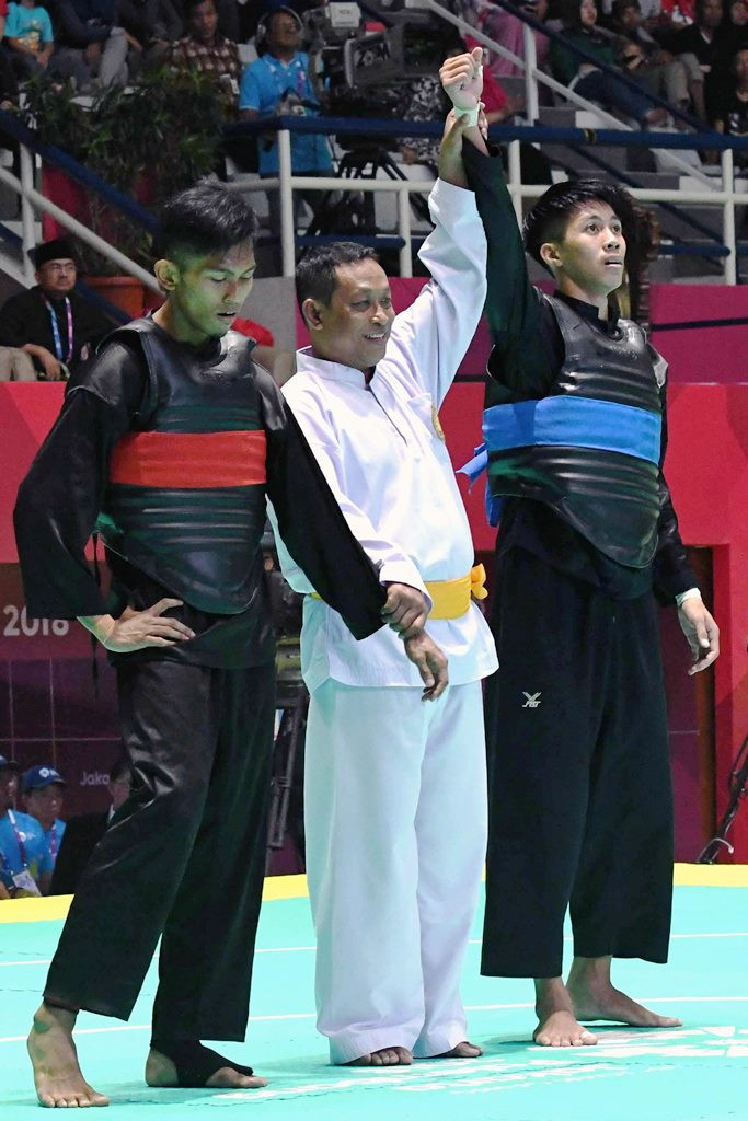 Pesilat Laos Mino Vongphakdy (kanan) dinyatakan sebagai pemenang oleh wasit dari pesilat Singapura Abdul Raaziq Abdul Rashid (kiri) dalam babak 16 besar Kelas D Putra Asian Games 2018. Peta kekuatan pencak silat di Asia relatif merata. INASGOC/Antara Foto/Dewi Nurcahyani