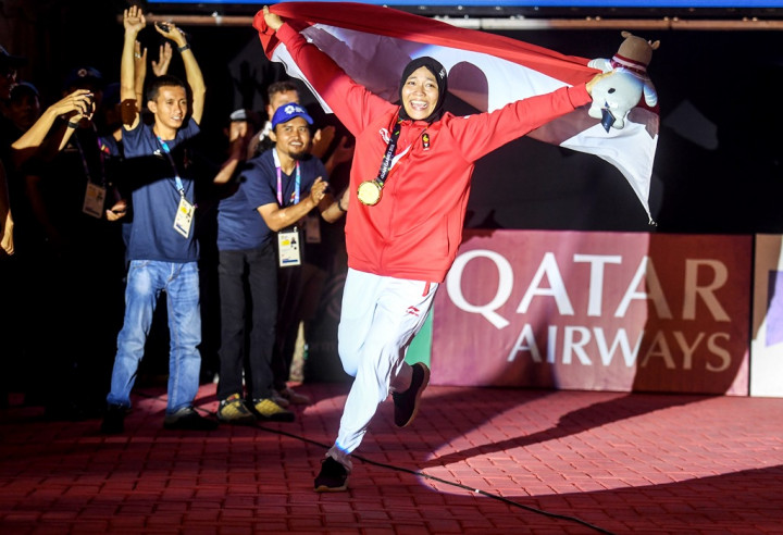 Aries Susanti Rahayu berlari berkeliling arena panjat tebing dengan mengibarkan bendera Merah Putih. Medali emas menggantung di lehernya.  INASGOC/Antara Foto/Hendra Nurdiyansyah