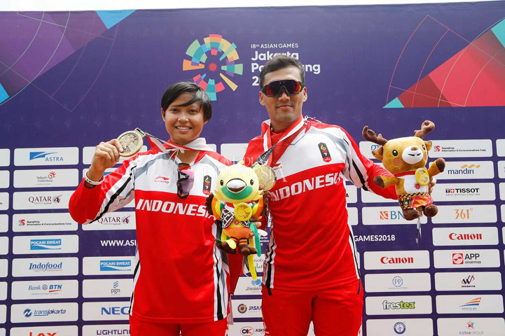 Pebalap sepeda BMX Indonesia I Gusti Bagus Saputra (kanan) dan Wiji Lestari memperlihatkan medali perak dan perunggu nomor final BMX Asian Games 2018 di Pulo Mas International BMX, Jakarta, Sabtu, 25 Agustus 2018.