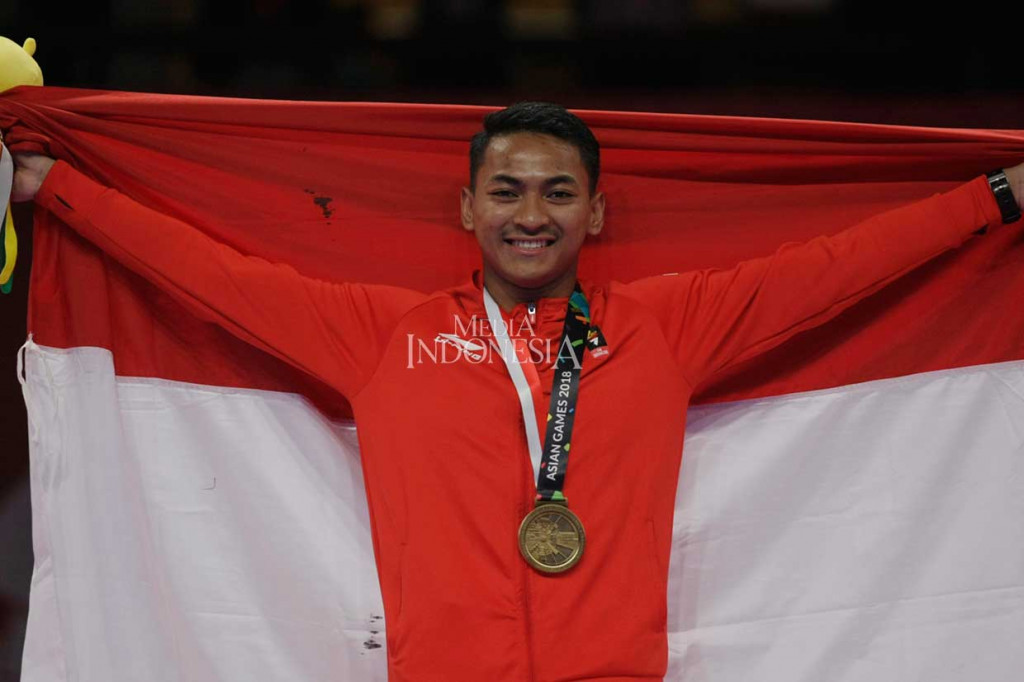 Karateka Indonesia Ahmad Zigi Zaresta Yuda membentangkan bendera Merah Putih setelah berhasil menyabet medali perunggu dalam kata perorangan putra Asian Games 2018.