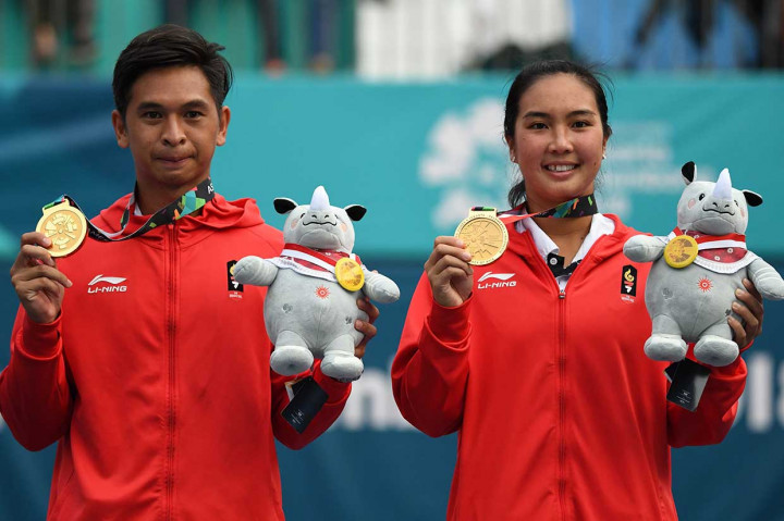 Ganda campuran Indonesia Christopher Rungkat/Aldila Sutjiati memperlihatkan medali emas yang baru saja mereka raih usai mengalahkan mengalahkan Sonchat/Luksika 6-4, 5-7, tie break 10-7 dalam waktu 1 jam 42 menit. 
