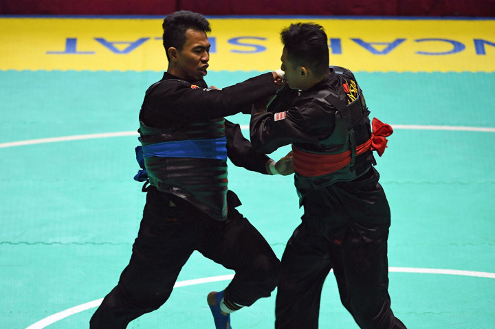 Pesilat Indonesia Amri Rusdana (kiri) melakukan pukulan kepada pesilat Malaysia Mohd Fauzi Khalid (kanan) dalam babak semifinal Kelas F Putra Asian Games 2018 di Padepokan Pencak Silat Taman Mini Indonesia Indah (TMII), Jakarta.