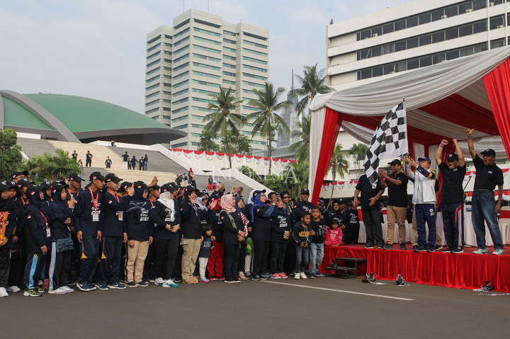Ketua MPR RI Zulkifli Hasan mengibarkan bendera saat melepas peserta Jalan Sehat Empat Pilar MPR di Komplek Parlemen, Senayan.