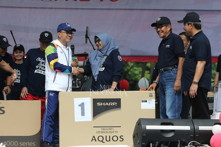 Ketua MPR RI Zulkifli Hasan (kiri) memberikan hadiah hasil pengundian kupon door price kepada peserta Jalan Sehat Empat Pilar MPR di Komplek Parlemen, Senayan.