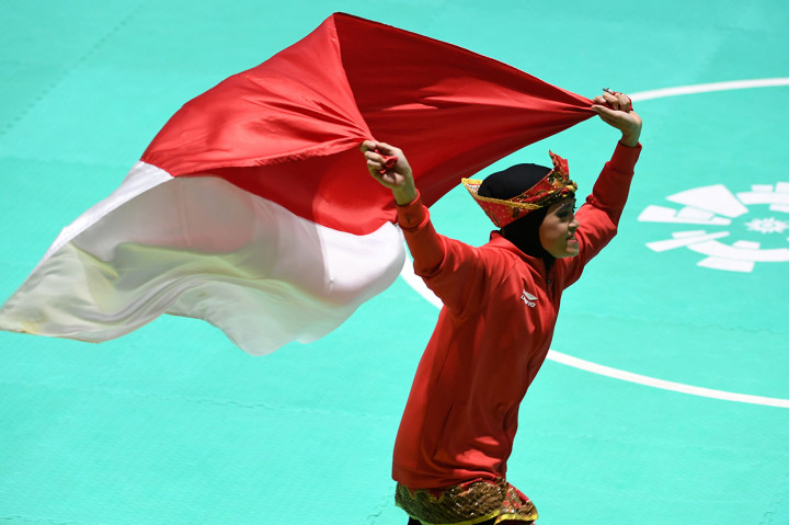 Pesilat Indonesia Puspa Arumsari membentangkan bendera merah putih saat merayakan kemenangan usai meraih medali emas nomor tunggal putri pencak silat seni Asian Games 2018 di Padepokan Pencak Silat Taman Mini Indonesia Indah (TMII), Jakarta. Antara Foto/INASGOC/Melvinas Priananda