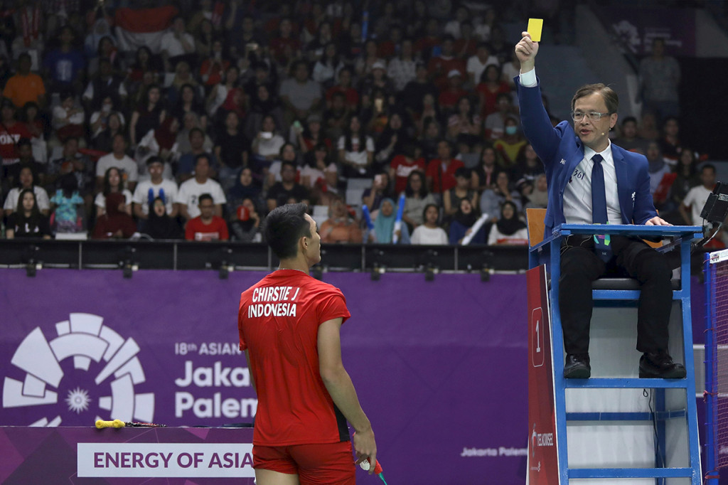 Wasit memberikan kartu kuning kepada pebulu tangkis tunggal putra Indonesia Jonatan Christie (kiri) saat bertanding melawan pebulu tangkis Jepang Kenta Nishimoto. Antara Foto/INASGOC/Nafielah Mahmudah