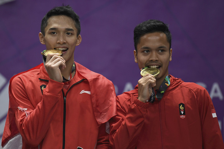 Pebulu tangkis tunggal putra Indonesia peraih medali emas Jonatan Christie dan peraih medali perunggu Anthony Sinisuka Ginting menggigit medali Asian Games 2018, usai upacara penyerahan medali di Istora Senayan, Jakarta. Antara Foto/INASGOC/Puspa Perwitasari