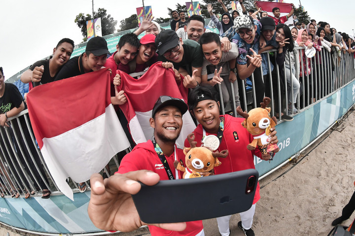 Pevoli pantai putra Indonesia Mohammad Ashfiya (kanan) dan Ade Candra Rachmawan (kiri) berswafoto bersama pendukung Indonesia usai menerima medali perak pada pertandingan final voli pantai putra Asian Games 2018 di arena Jakabaring Sport City, Palembang, Sumsel. Antara Foto/INASGOC/Muhammad Adimaja