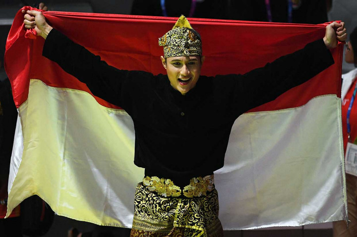 Pesilat Indonesia Sugianto membentangkan bendera Merah Putih usai tampil dan meraih medali emas dalam babak final tunggal putra pencak silat seni Asian Games 2018 di Padepokan Pencak Silat Taman Mini Indonesia Indah (TMII), Jakarta, Rabu.