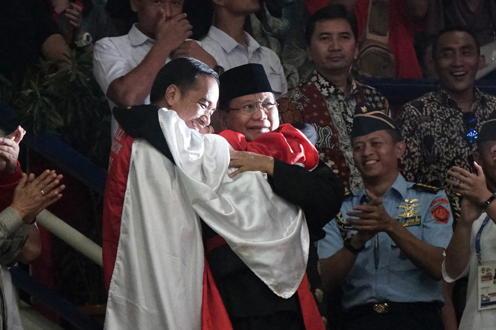 Joko Widodo dan Prabowo Subianto berpelukan saat pesilat Indonesia Hanifan Yudani melakukan selebrasi kemenangannya. Antara Foto/INASGOC/Aditia Noviansyah

