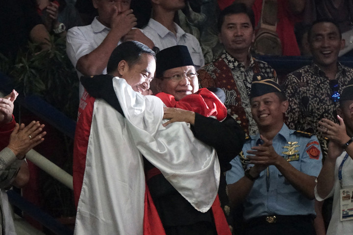 Joko Widodo dan Prabowo Subianto berpelukan saat pesilat Indonesia Hanifan Yudani melakukan selebrasi kemenangannya. Antara Foto/INASGOC/Aditia Noviansyah
