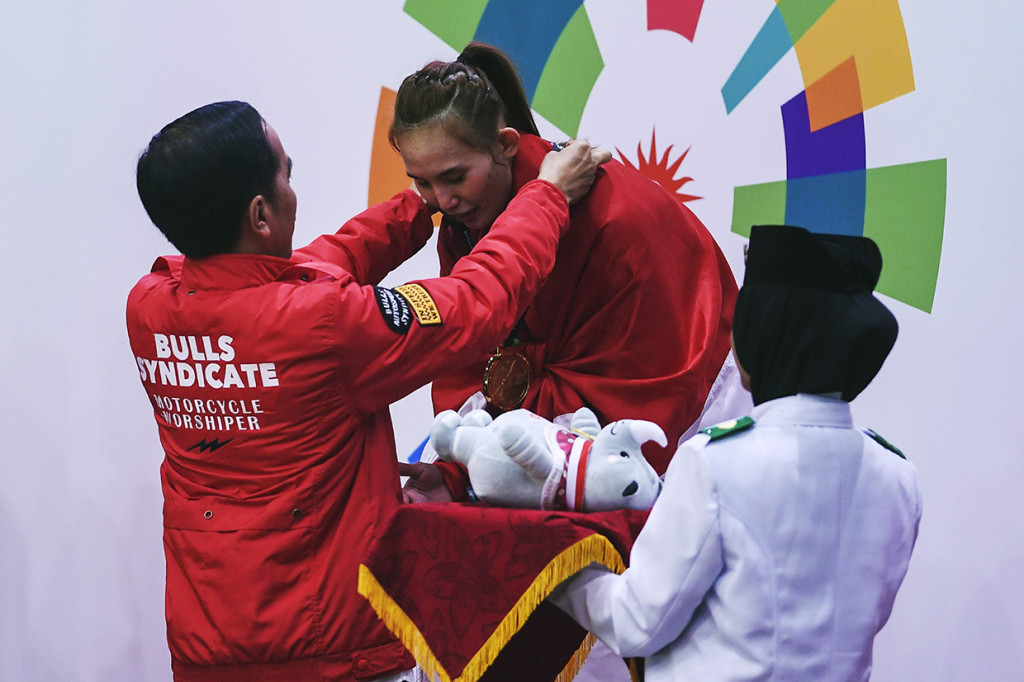 Presiden Joko Widodo memberikan medali emas kepada pesilat Indonesia Wita Wewey seusai mengalahkan pesilat Vietnam Thi Tem Tran pada final pencak silat kelas 50-55 kg putri Asian Games 2018 di Padepokan Pencak Silat, TMII. Afp Photo/Chaideer Mahyuddin