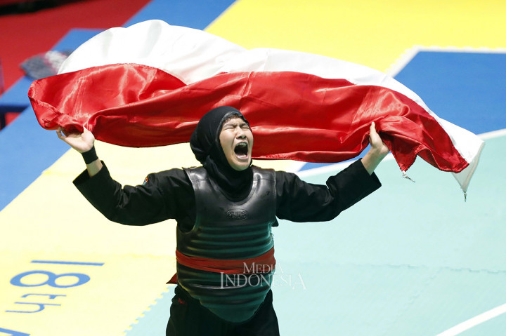 Pesilat Indonesia Pipiet Kamelia membawa bendera merah putih seusai memenangkan final pencak silat kelas 60-65 kg putri Asian Games 2018 melawan pesilat Vietnam Thi Cam Nhi Nguyen di Padepokan Pencak Silat, TMII, Jakarta. MI/Rommy Pujianto