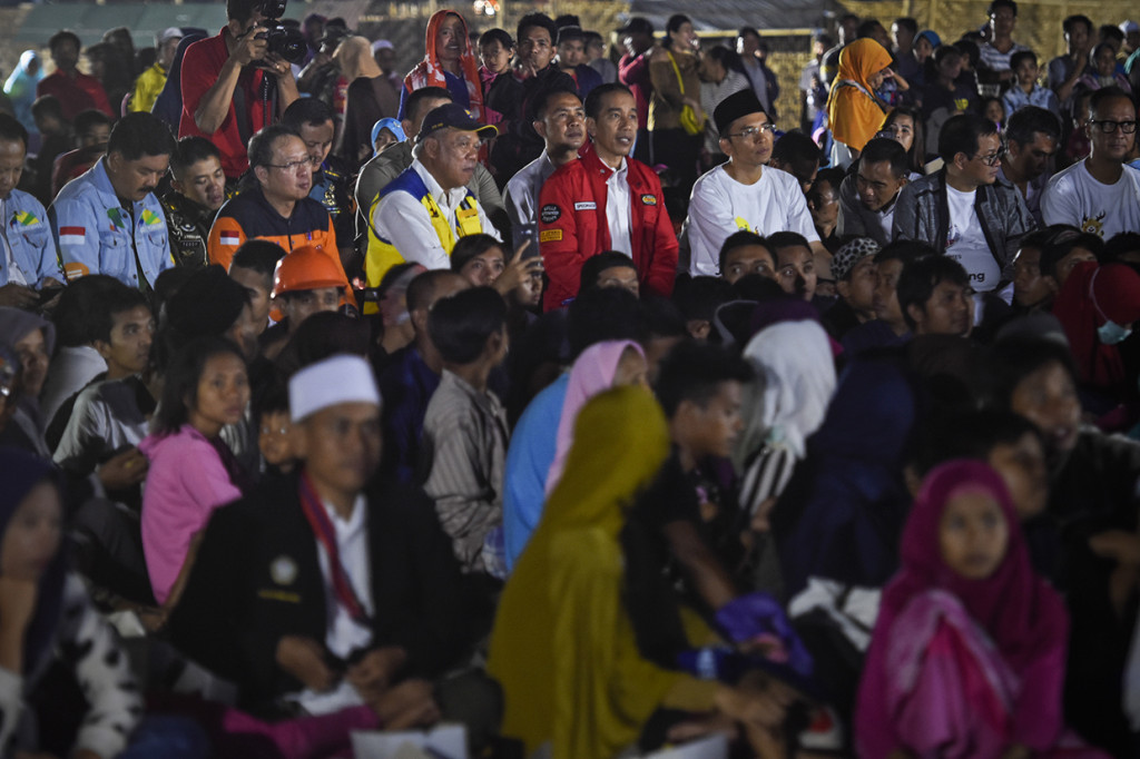 Presiden Joko Widodo (tengah) didampingi Gubernur NTB TGB Zainul Majdi (ketiga kanan) bersama warga korban gempa nonton bareng upacara penutupan Asian Games 2018 di Lapangan Kecamatan Gunungsari, Lombok Barat, NTB.