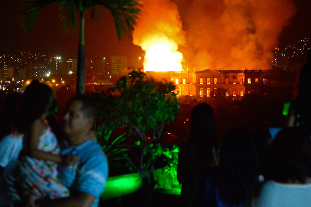 Warga menyaksikan api yang melalap gedung museum nasional Brasil di Rio de Janeiro. Bangunan ini merupakan institusi sains tertua di negeri itu.