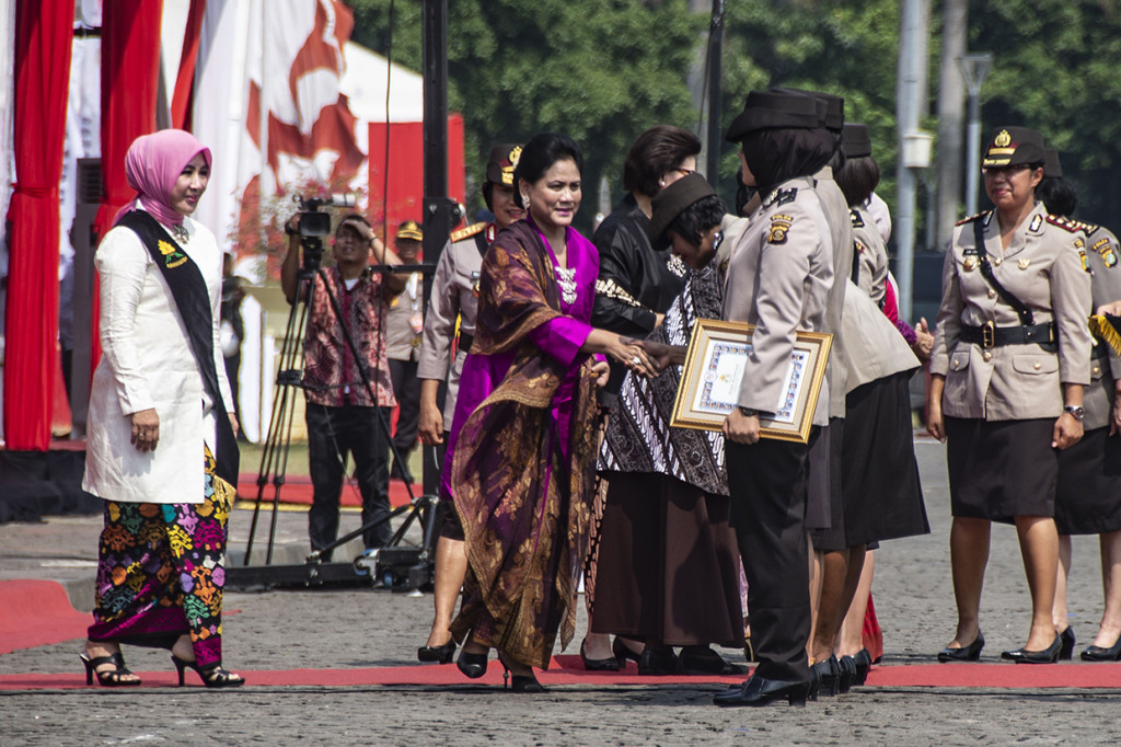Ibu Negara Iriana Joko Widodo (tengah) disaksikan Ibu Asuh Polwan Tri Tito Karnavian (kiri) memberi selamat kepada Polwan berprestasi pada peringatan HUT Ke-70 Polwan di Monas, Jakarta. 
