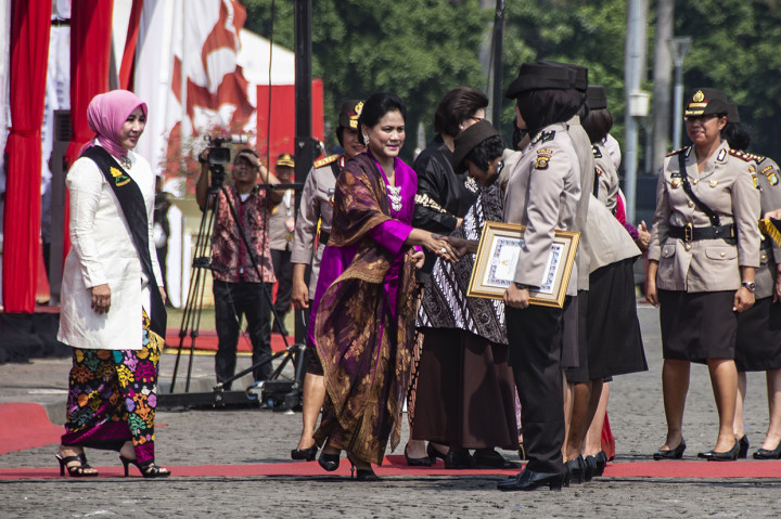 Ibu Negara Iriana Joko Widodo (tengah) disaksikan Ibu Asuh Polwan Tri Tito Karnavian (kiri) memberi selamat kepada Polwan berprestasi pada peringatan HUT Ke-70 Polwan di Monas, Jakarta. 
