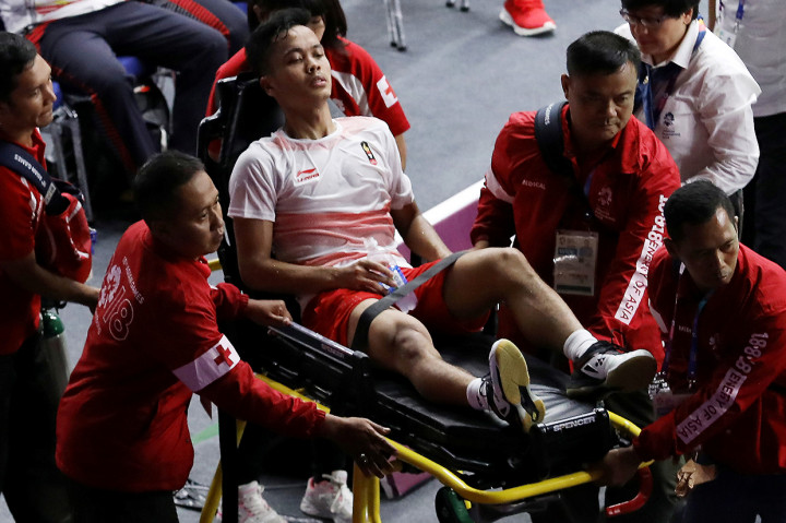Petugas medis membantu pebulu tangkis tunggal putra Indonesia Anthony Sinisuka Ginting yang mengalami cedera saat melawan pebulu tangkis tunggal putra Cina Shi Yuqi pada set ketiga babak final beregu putra Asian Games 2018 di Istora Senayan, Jakarta, Rabu (22/8). Antara Foto/ INASGOC/Nafielah Mahmudah