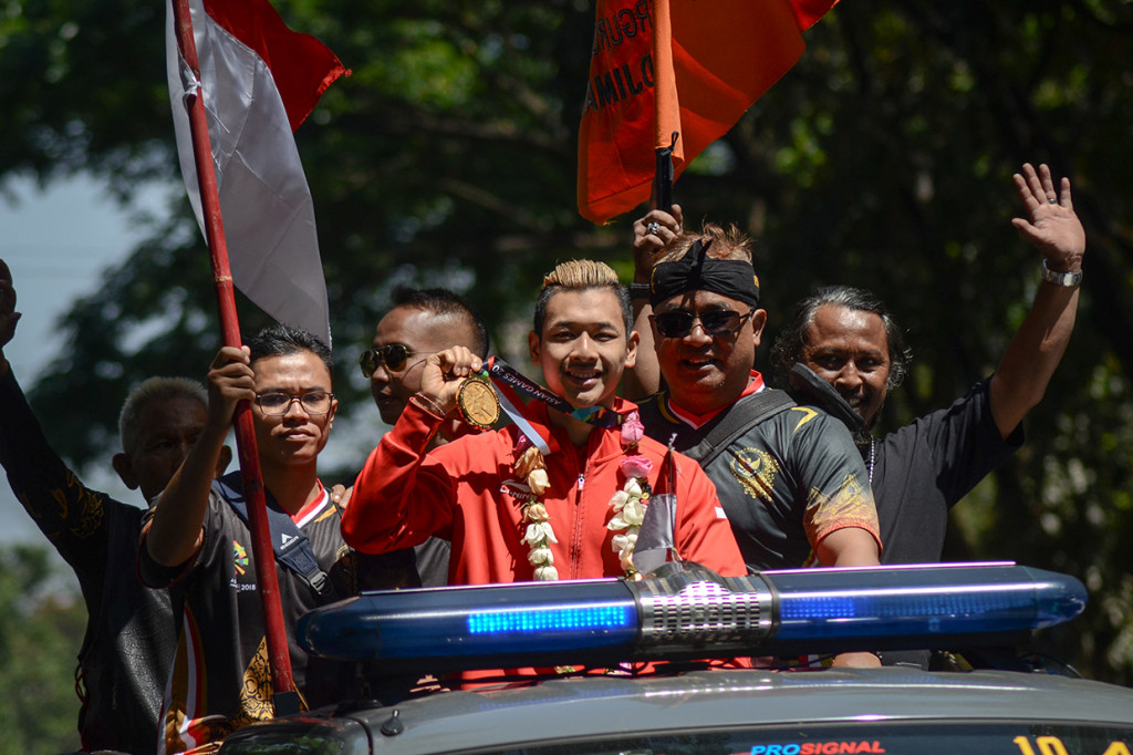 Peraih medali emas cabang olahraga silat dalam perhelatan Asian Games 2018 Hanifan Yudani Kusuma (tengah) menunjukkan medalinya saat pawai penyambutan di Bandung, Jawa Barat, Senin (3/9). Penyambutan yang diinisiasi oleh Ikatan Pencak Silat Indonesia (IPSI) Jabar tersebut dilakukan dalam rangka merayakan prestasi yang diraih oleh atlet silat Jabar yang meraih empat dari 14 medali emas dalam cabang olahraga silat. Antara Foto/Raisan Al Farisi
