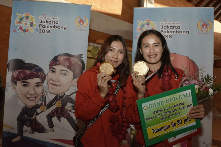 Peraih medali emas cabang olahraga pencak silat Asian Games 2018 Sang Ayu Sidan Wilantari (kanan) dan Ni Made Dwiyanti menujukkan medali yang mereka raih saat tiba di Bandara I Gusti Ngurah Rai, Badung, Bali, Senin (3/9). Ratusan warga menyambut para atlet asal Bali yang berhasil meraih medali Asian Games 2018. Mereka juga akan mendapat bonus tambahan dari Pemerintah Provinsi Bali. Antara Foto/Fikri Yusuf