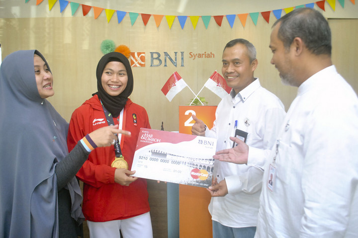 Atlet Taekwondo peraih medali emas pertama Asian Games 2018 menerima buku tabungan, kartu haji dan umroh serta Hasanah Card di kantor cabang BNI Syariah Bogor, Jawa Barat, Selasa (4/9). Bank BNI Syariah dalam rangka memperingati Hari Pelanggan Nasional melakukan apresiasi terhadap atlet Defia Rosmaniar untuk mewujudkan niatnya menunaikan ibadah haji ke tanah suci Mekkah melalui tabungan BNI Baitullah IB Hasanah. Antara Foto/Arif Firmansyah