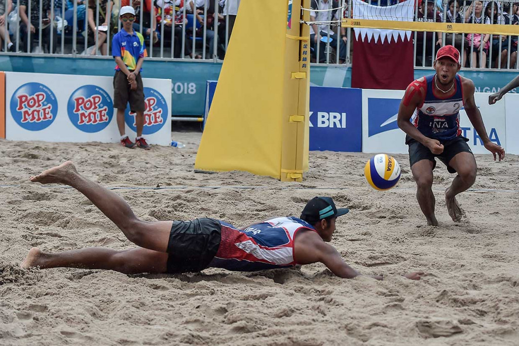Pevoli pantai putra Indonesia Mohammad Ashfiya (kiri) dan Ade Candra Rachmawan mencoba mengembalikan bola ke arah pevoli Qatar. INASGOC/Antara Foto/Muhammad Adimaja