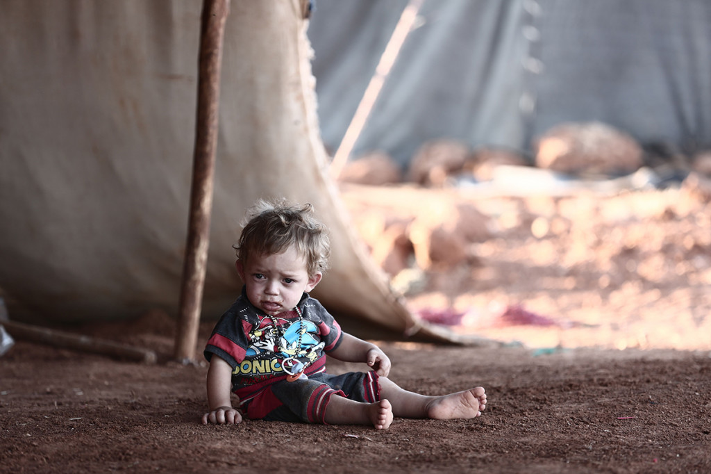 Seorang anak duduk di depan sebuah tenda di sebuah kamp untuk para pengungsi dari provinsi Idlib yang dikuasai pemberontak, di desa al-Ghadfa. Afp Photo/Nazeer Al Khatib
