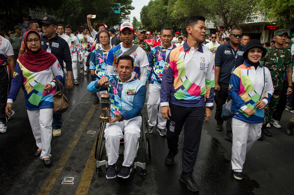 Atlet Paragames, Jaenal Aripin (tengah) bersama Ketua INAPGOC, Raja Sapta Oktohari (kedua kanan) membawa lentera api pada Pawai Api Obor Asian Para Games 2018 di Solo, Jawa Tengah.