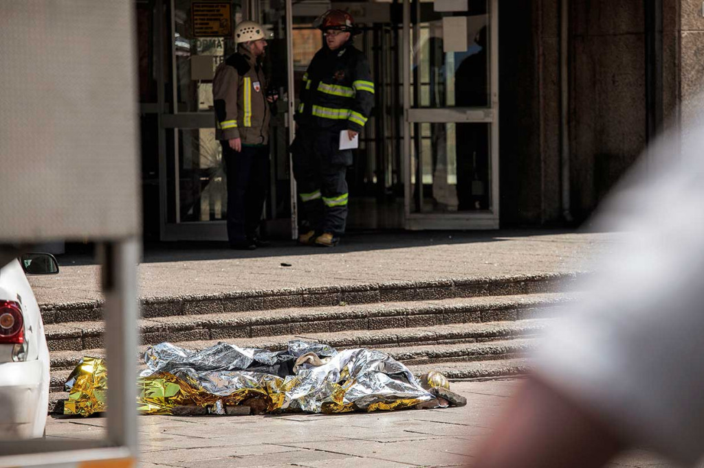 Seorang petugas pemadam kebakaran yang tewas ditutupi terpal setelah terjatuh dari lantai 23 saat berusaha memadamkan api di gedung 24 lantai di Johannesburg, Afrika Selatan, Rabu, 5 September. Menurut kepala keamanan kota, korban diduga terpeleset. 