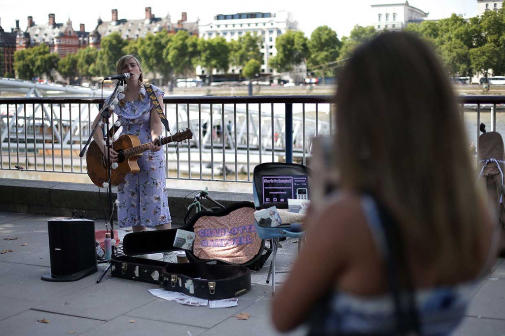 Charlotte Campbell, seorang pengamen yang menyediakan mesin pembaca kartu e-money bagi pejalan kaki yang akan memberi sumbangan selain uang tunai di London, Inggris, 1 September lalu.