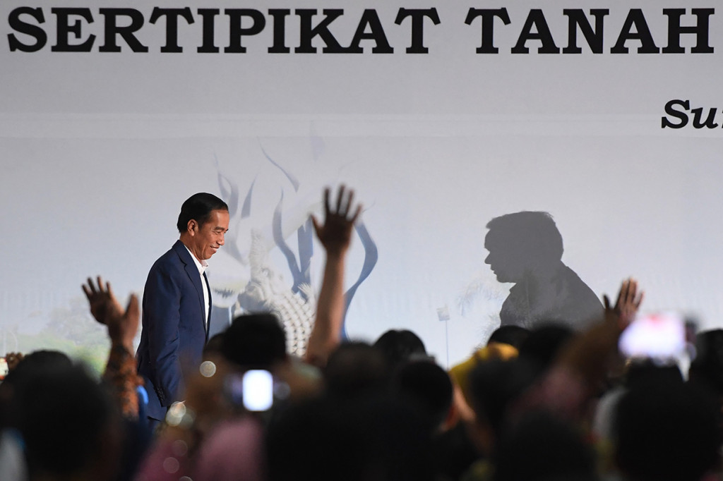 Presiden Joko Widodo (kiri) menaiki panggung untuk memberikan arahan saat penyerahan sertifikat tanah untuk rakyat di Surabaya. Antara Foto/Zabur Karuru
