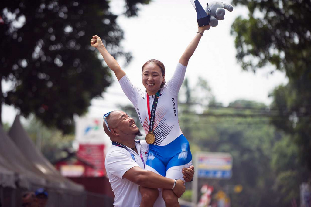 Pembalap sepeda Korea Selatan Ahreum Na dibopong pelatihnya usai meraih medali emas nomor Cycling Road Women Individual Time Trial 18,7 km. INASGOC/Antara Foto/Septianjar Muharam