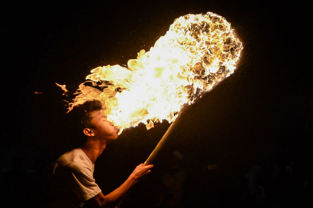 Seorang warga menyemburkan bahan bakar ke api saat mengikuti pawai obor di Desa Cibiru Hilir, Cileunyi, Kabupaten Bandung, Jawa Barat, Senin (10/9) malam.