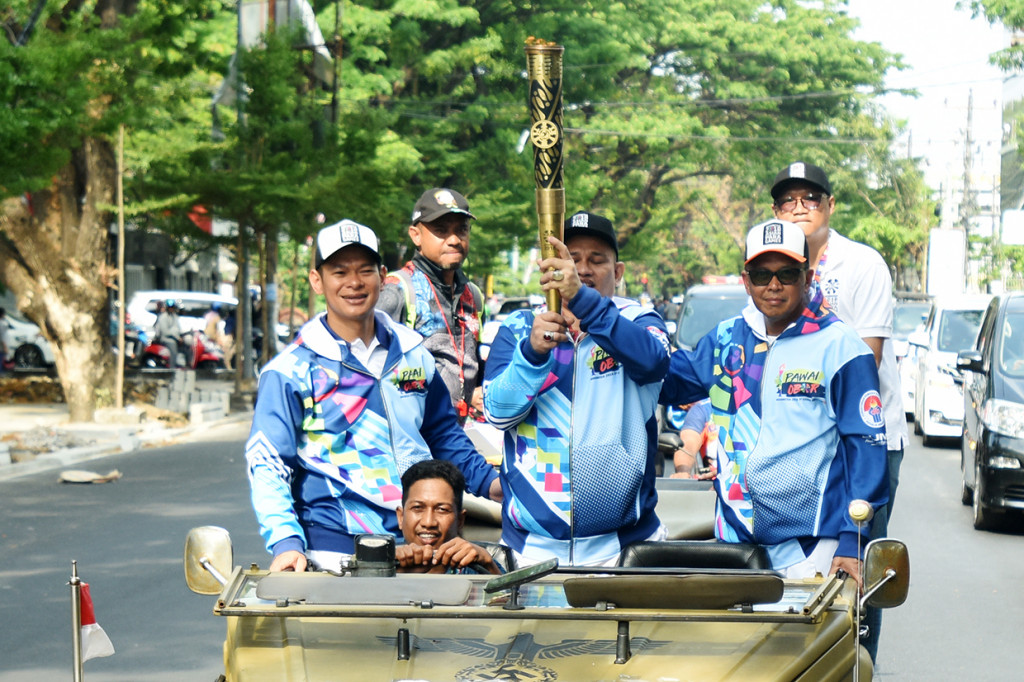 Gubernur Sulsel Nurdin Abdullah (kanan) bersama Ketua Panitia Pelaksana Asian Para Games (Inapgoc) Raja Sapta Oktohari (kiri) dan atlet lempar lembing Bahar Rahman (tengah) membawa obor saat Pawai Obor Asian Para Games di Makassar, Sulawesi Selatan.
