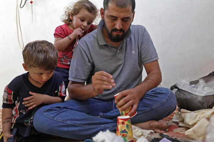 Hadheefa al-Shahadh, 27, tengah melubangi sebuah cangkir plastik yang akan digunakannya sebagai masker mengantisipasi jika serangan senjata kimia kembali terjadi di Idlib, Suriah, Selasa, 11 September 2018.